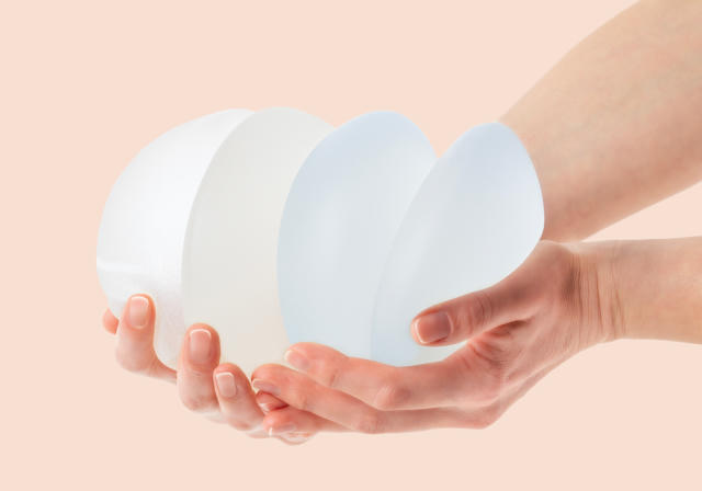 Hands holding multiple breast implant samples showing different sizes and profiles